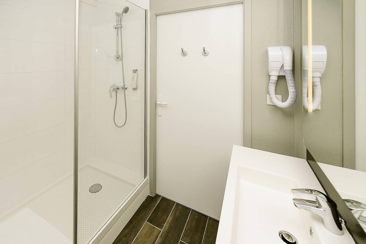 A bathroom with a shower, a sink, and a mirror.