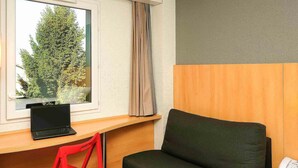 A room with a wooden desk, a black chair, a red chair, and a black sofa. - ibis Lyon Est Beynost A42 (Beynost)