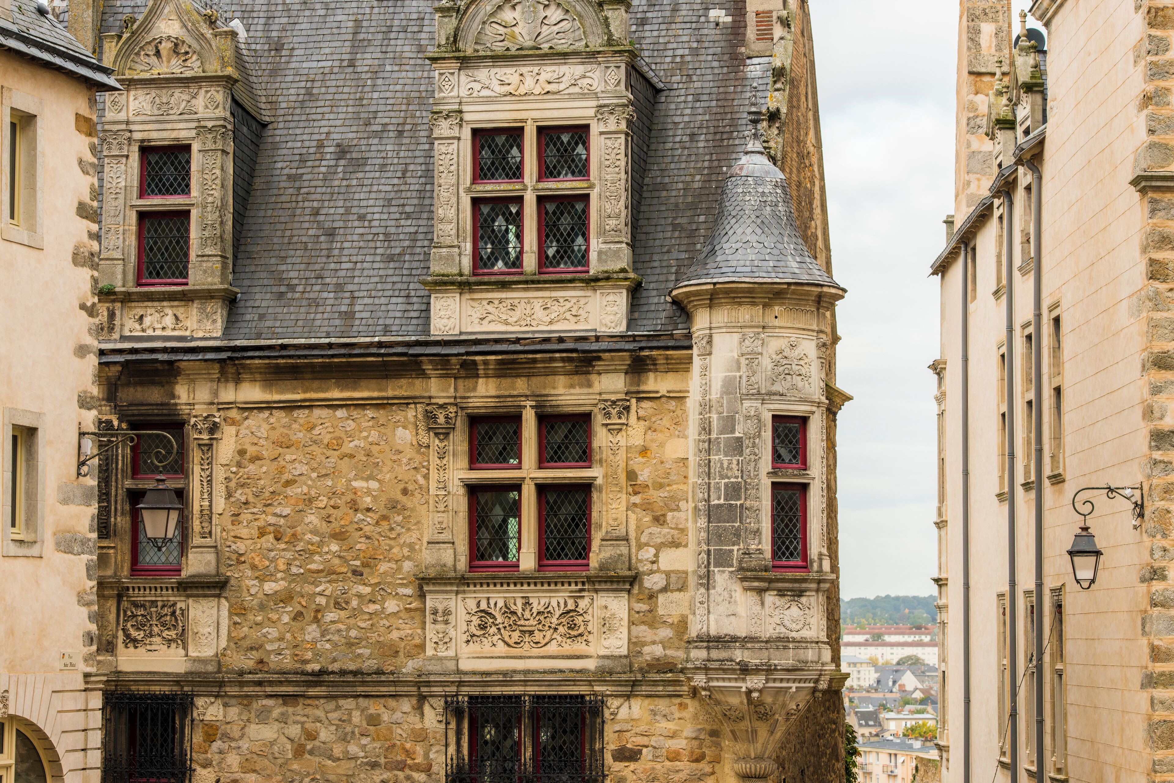 A historic stone building with ornate window frames and a turret.