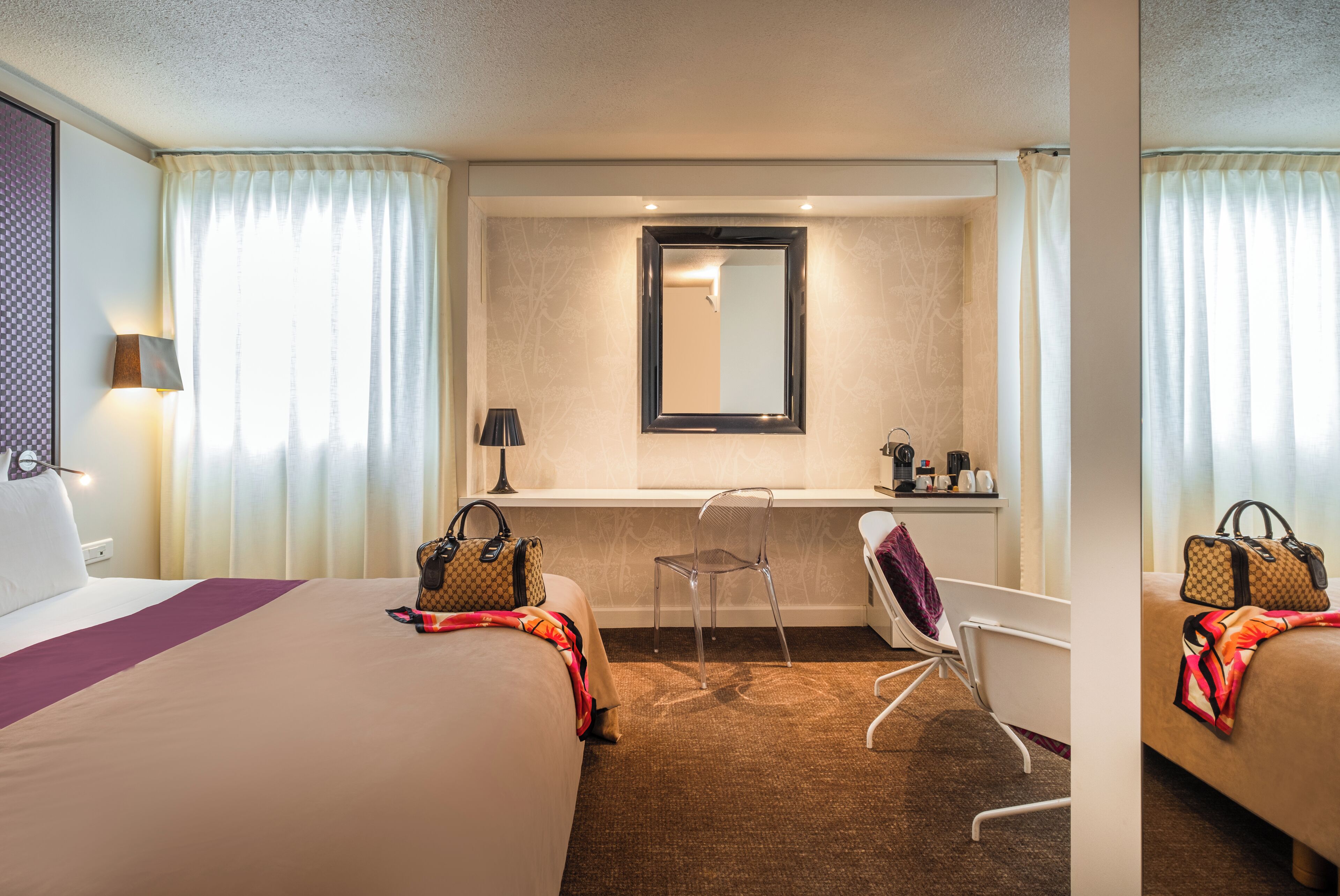 Ein Hotelzimmer mit einem großen Bett, einem Schreibtisch mit Stuhl, einem Spiegel und einem Fenster mit Vorhängen.