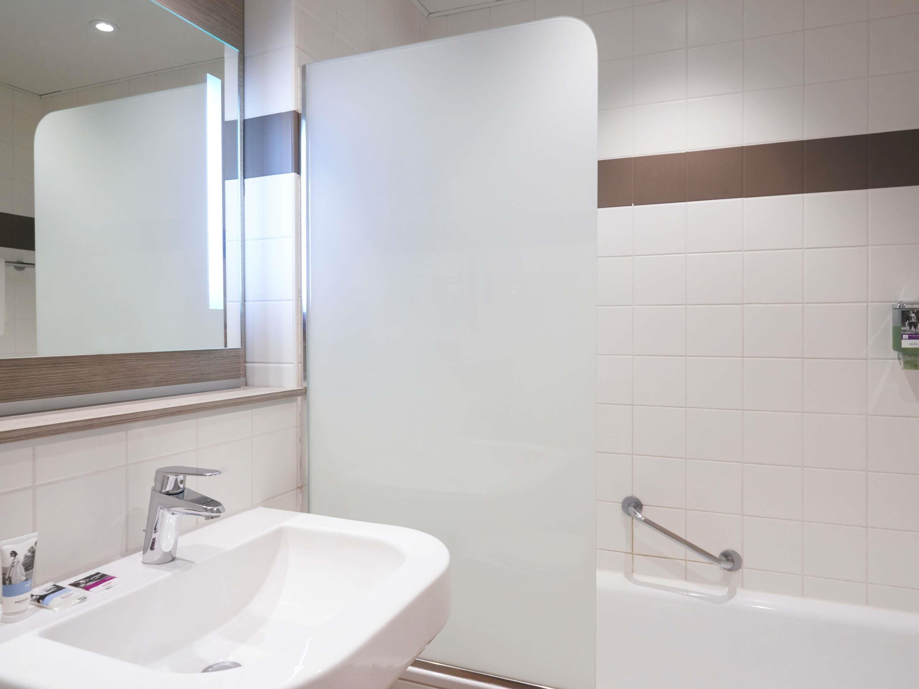 A bathroom with a sink, mirror, and shower.