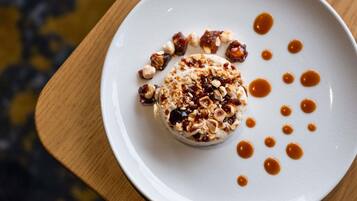 Un dessert servi dans une assiette blanche, nappé de caramel et parsemé de noix.