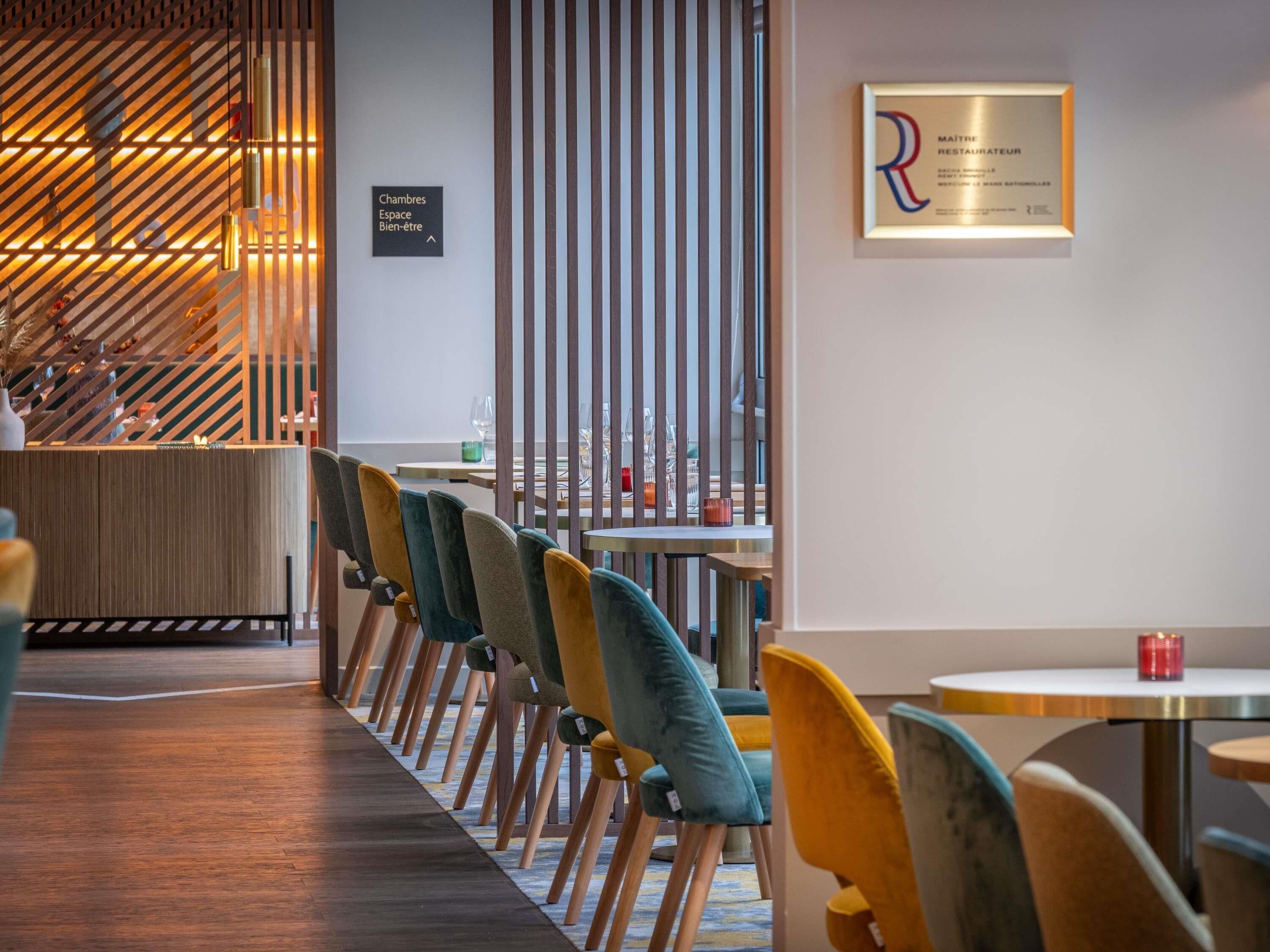 A modern interior with a row of chairs, a reception desk, and a wall-mounted sign.