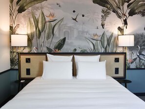 A bed with white linens, two bedside lamps, and a wall mural with tropical plants and birds. - Mercure Le Mans Batignolles - Hôtel & Spa (Le Mans)