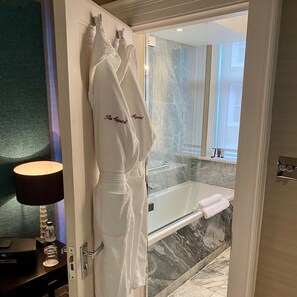 A bathroom with a glass shower enclosure, a marble-tiled floor, and a towel rack with white robes. - The Capital Hotel, Apartments & Townhouse - Small Luxury Hotels of The World (London)