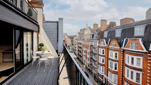 A balcony with a table and chairs, overlooking a row of traditional brick buildings with multiple stories and balconies. - The Capital Hotel, Apartments & Townhouse - Small Luxury Hotels of The World (London)