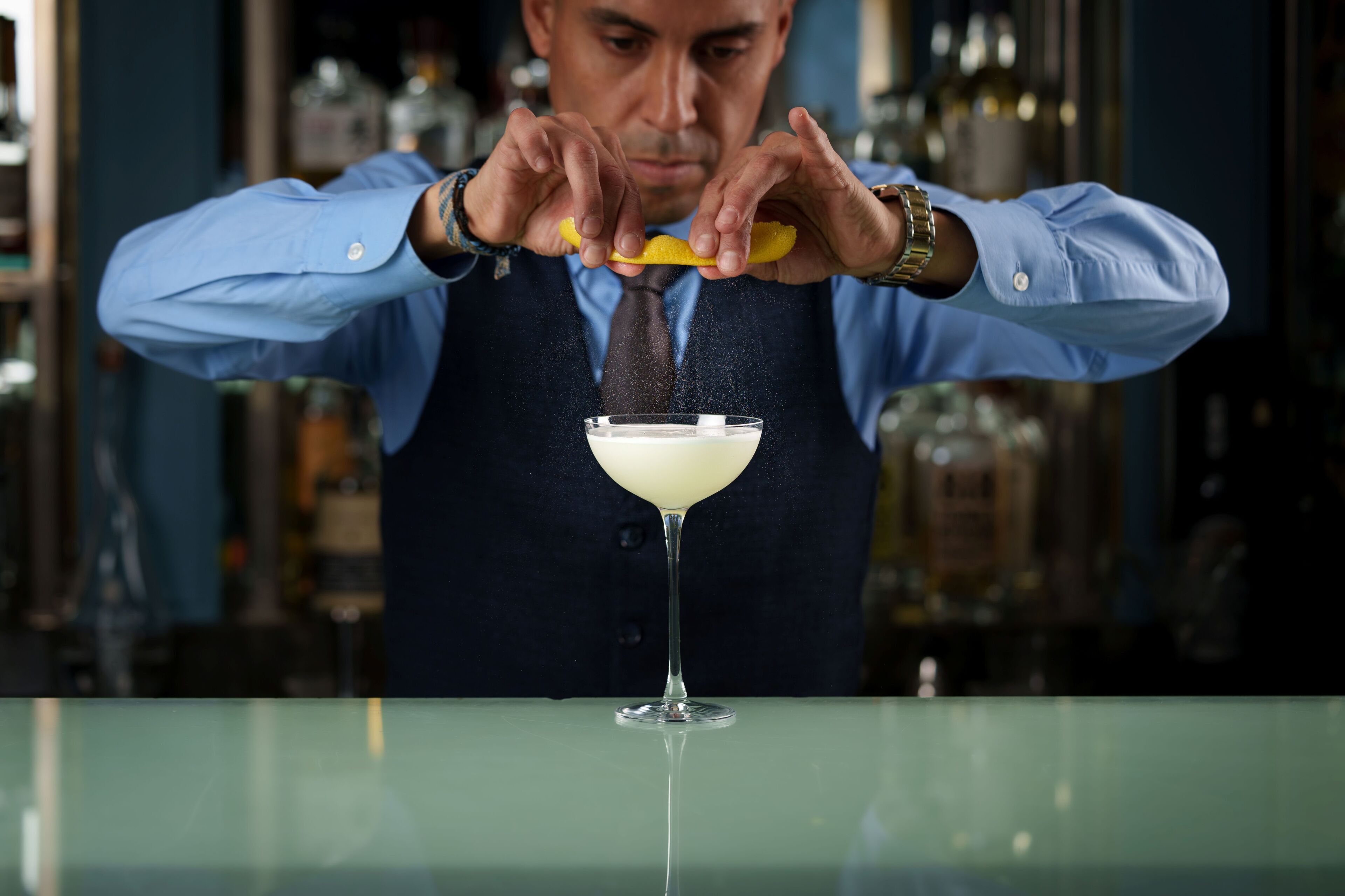 A bartender preparing a cocktail in a bar setting.