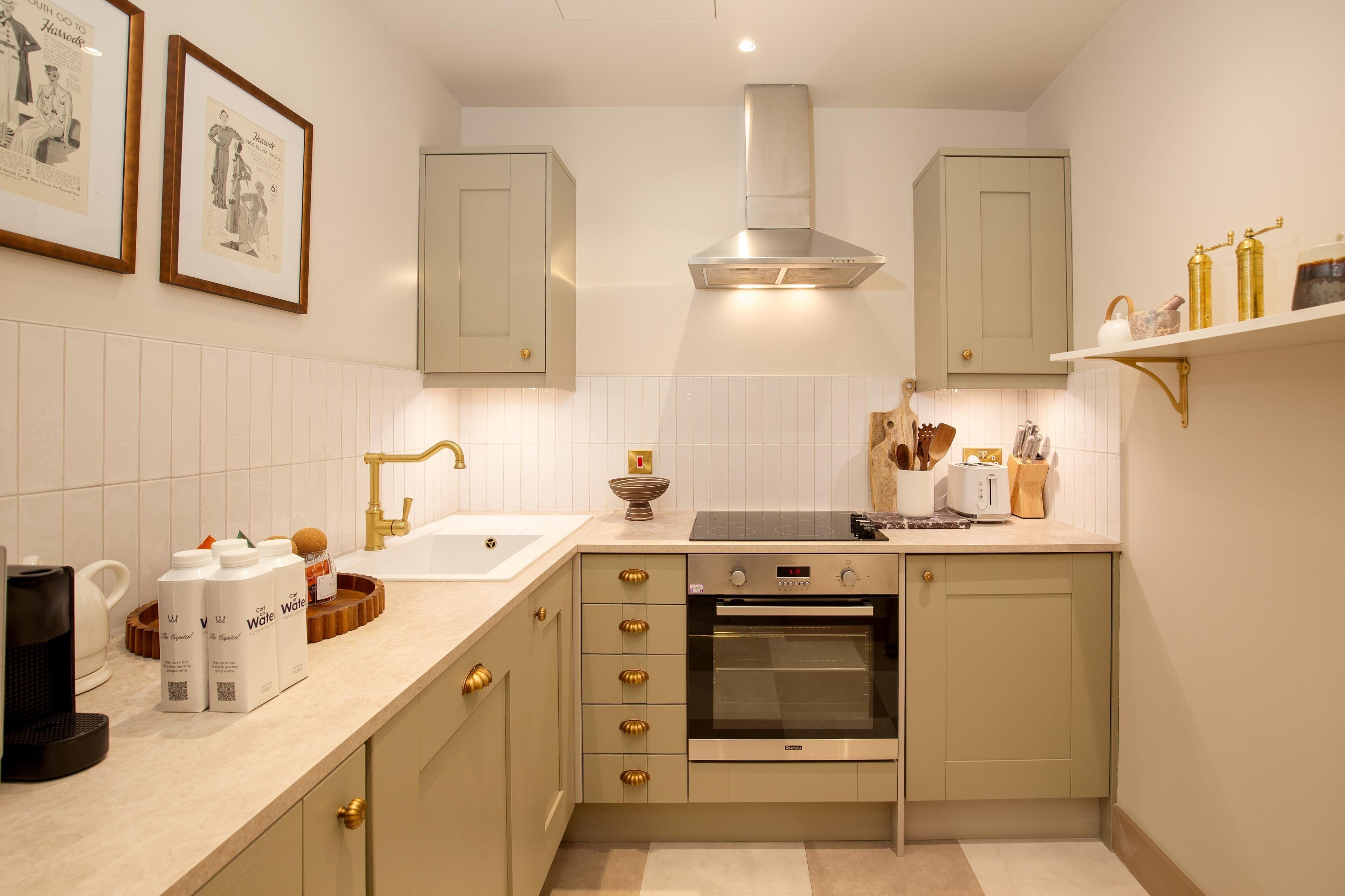 A kitchen with a built-in oven, a sink, and a countertop with a coffee maker and milk cartons.