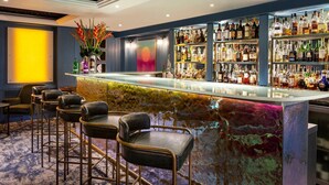 A bar area with a marble counter, multiple liquor bottles, and leather bar stools. - The Capital Hotel, Apartments & Townhouse - Small Luxury Hotels of The World (London)