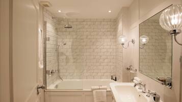 Un baño con ducha envuelta en vidrio, una bañera blanca y un lavabo con espejo.