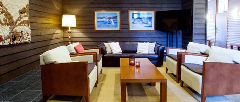 A modern lobby with a sofa set, a coffee table, and a flat-screen TV.
