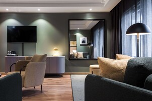 A modern living room with a flat-screen TV, a sofa, a coffee table, and a lamp.