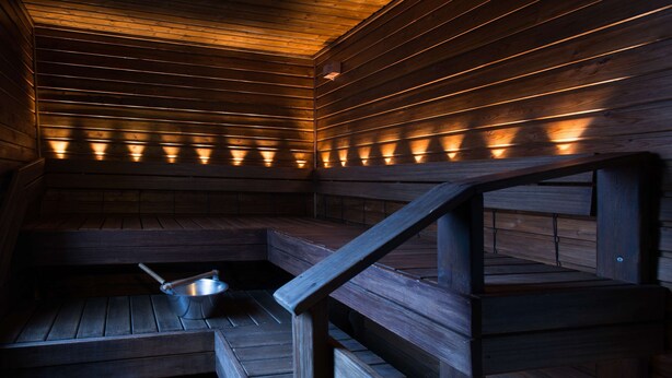 A sauna with wooden benches and a metal basin.