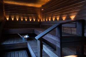 A sauna with wooden benches and a metal basin. - Scandic Rukahovi (Kuusamo)