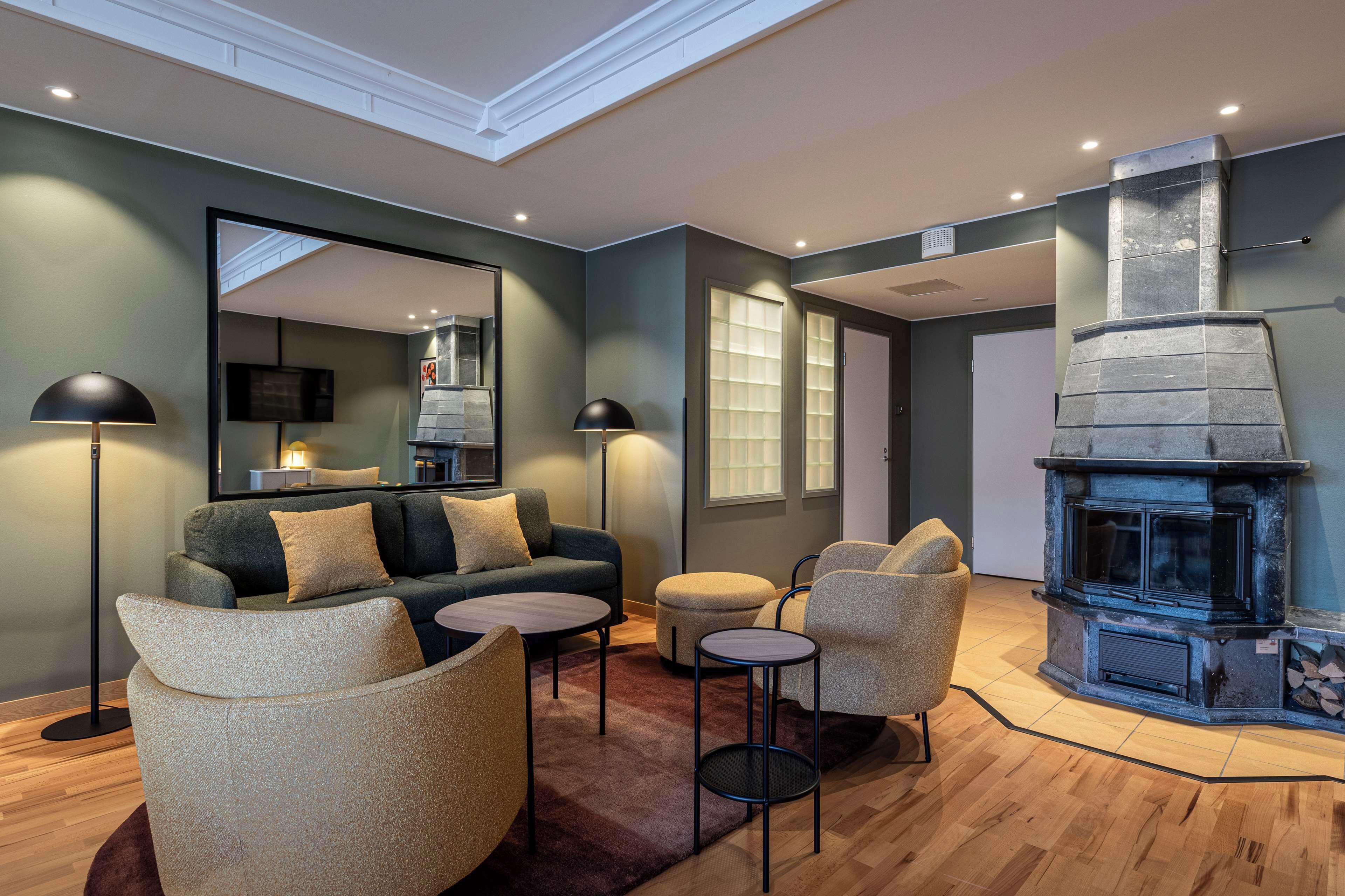 A modern living room with a fireplace, a sofa, armchairs, and a coffee table.