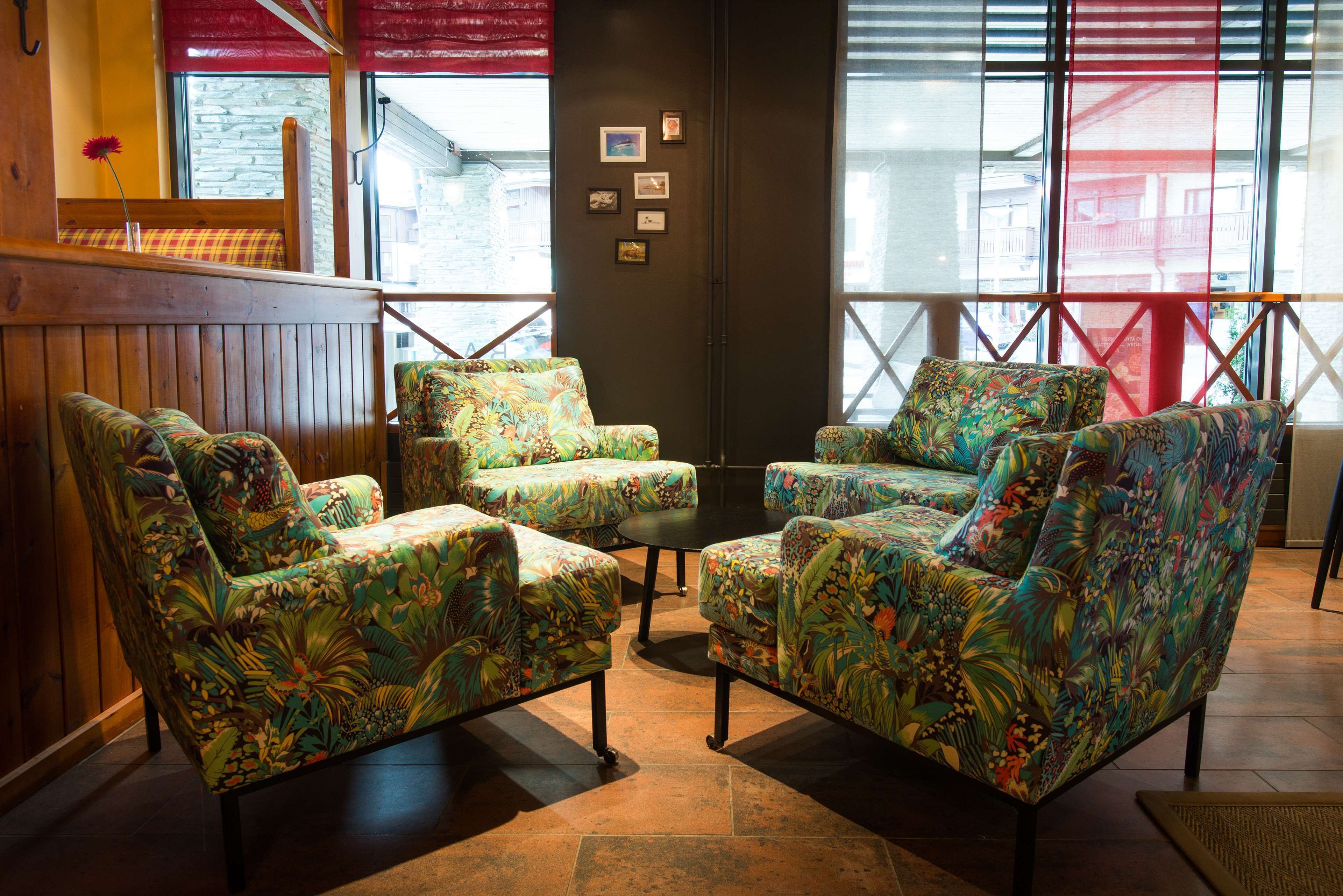 Un espace détente avec des chaises à motifs floraux et une petite table, un banc en bois et un mur orné de tableaux.