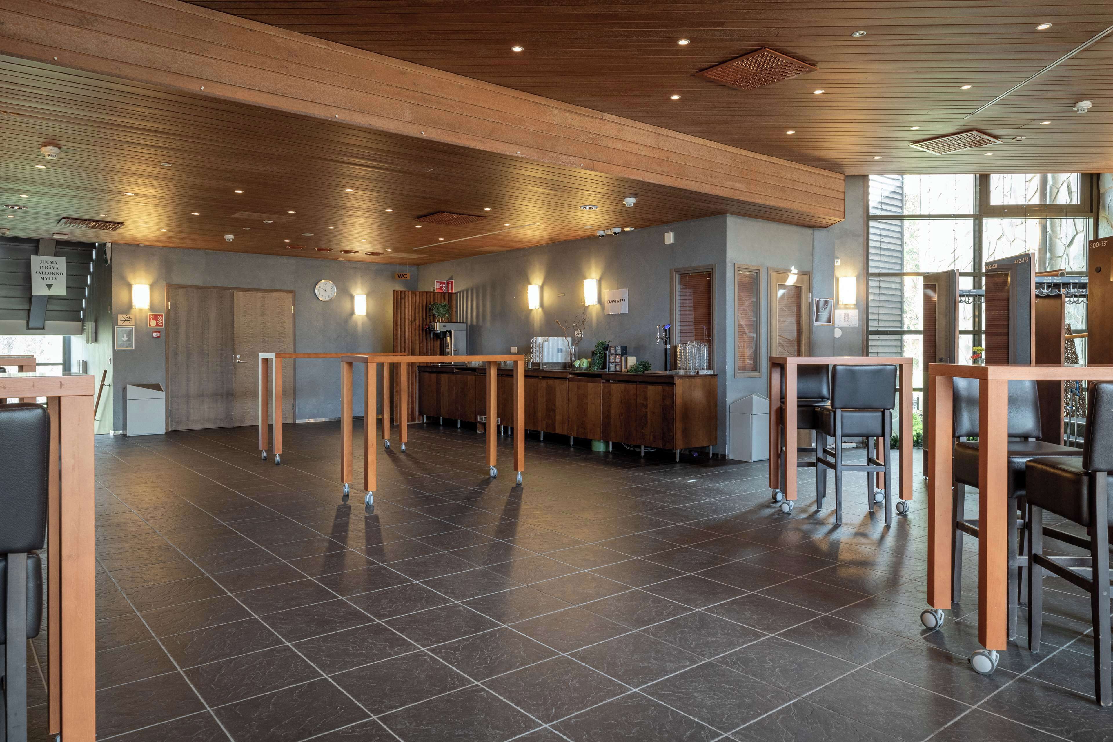 Un'ampia hall con soffitto in legno, una reception e un'area bar.