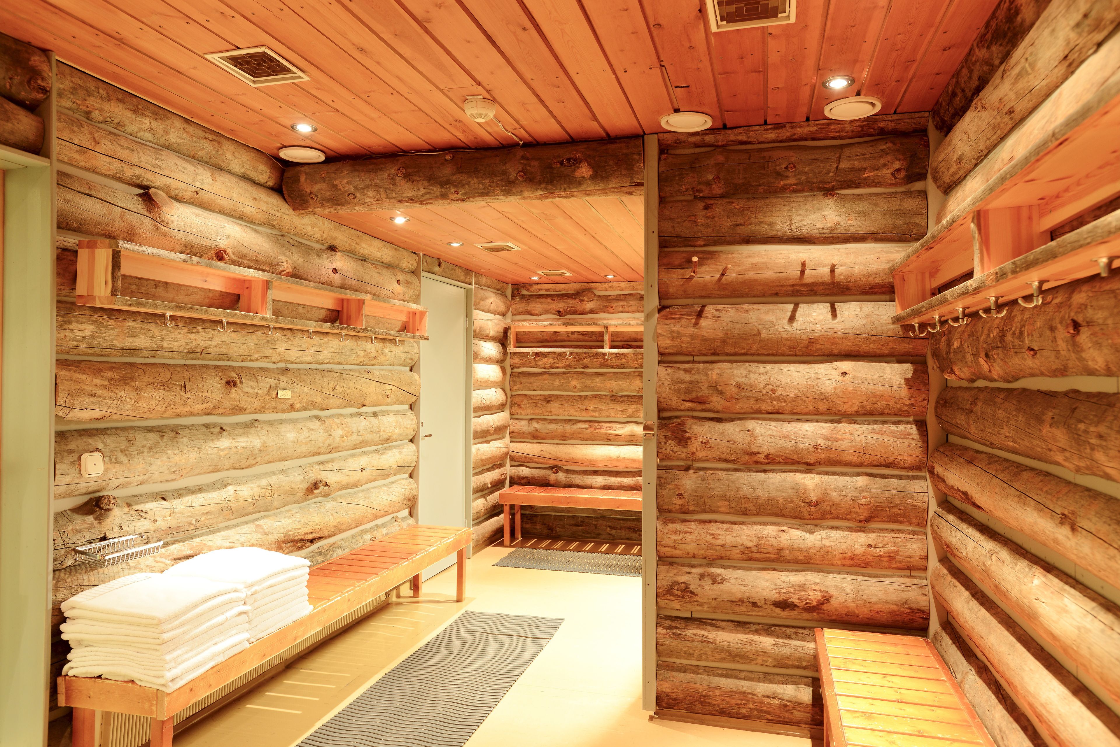 Ein rustikales Holzhaus-Interieur mit Holzwänden, einer Bank und einem Stapel Handtücher.