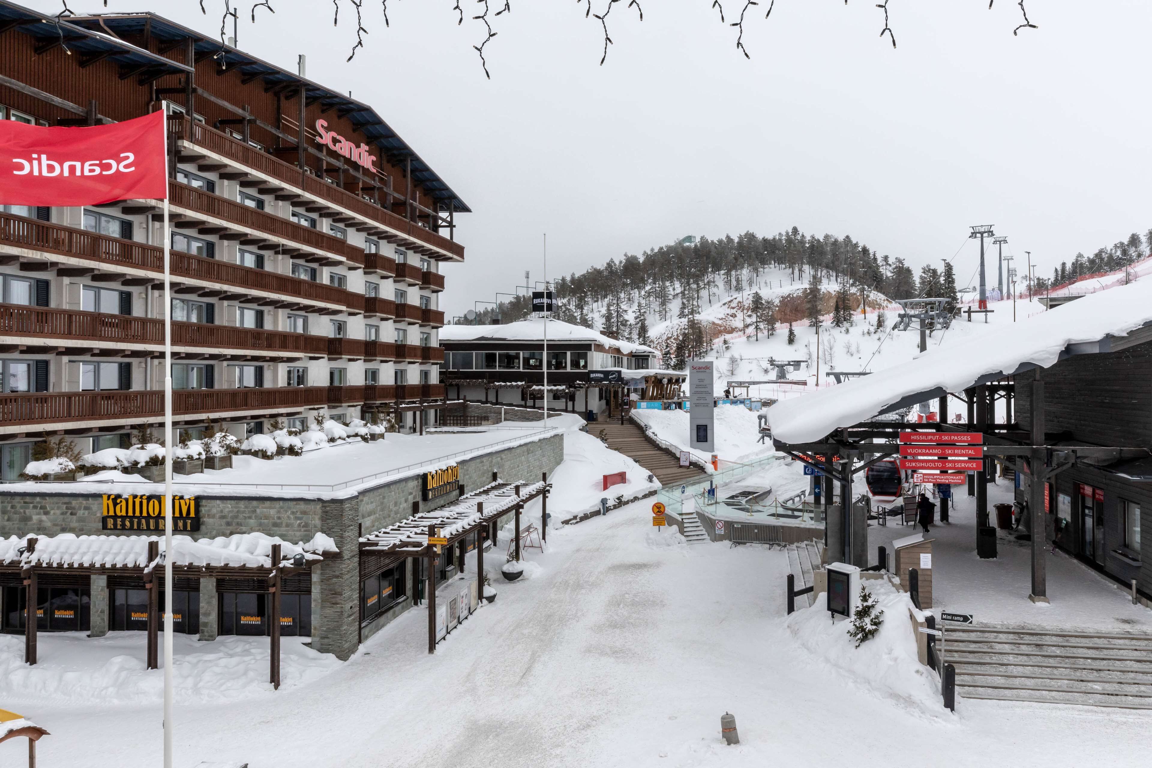 A hotel with multiple floors, a ski lift in the background, and a snowy landscape.