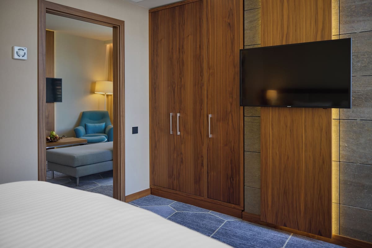 Een hotelkamer met een bed, een kledingkast, een televisie en een zithoek met een lamp.