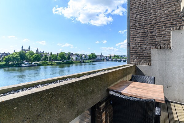 Un balcón con vistas a un río y edificios a lo lejos.
