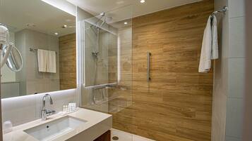 Een moderne badkamer met een glazen douchecabine, een grote spiegel en een houten wand.