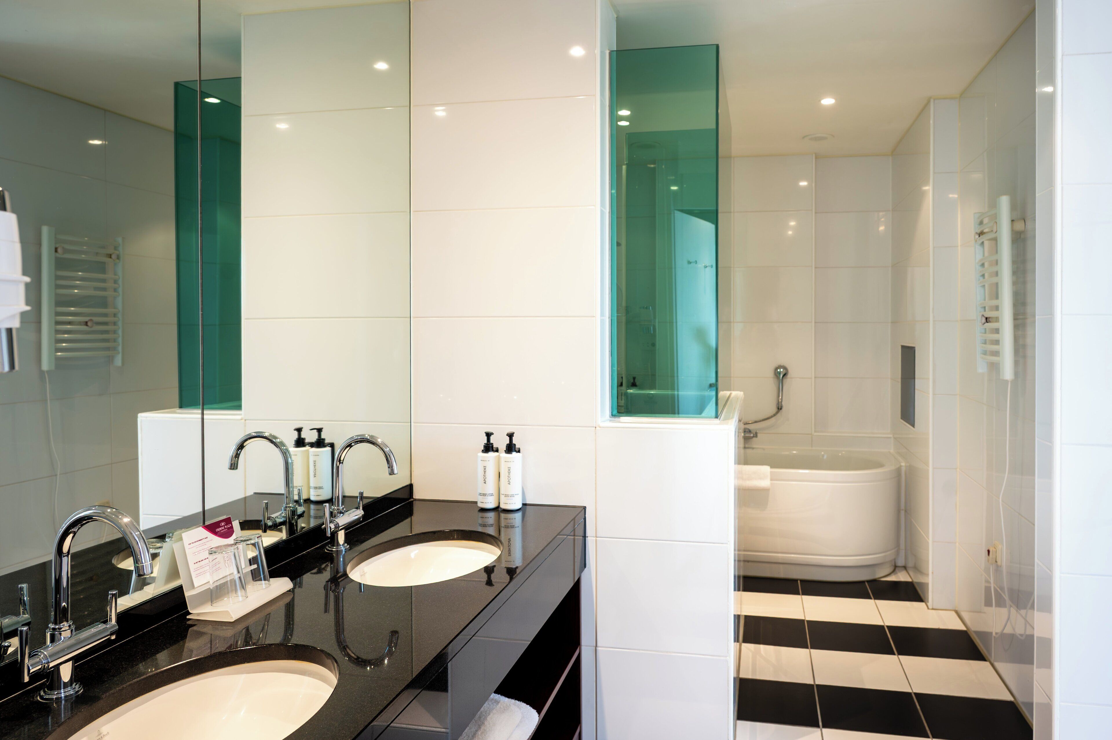 A modern bathroom with two sinks, a large mirror, and a separate shower area.