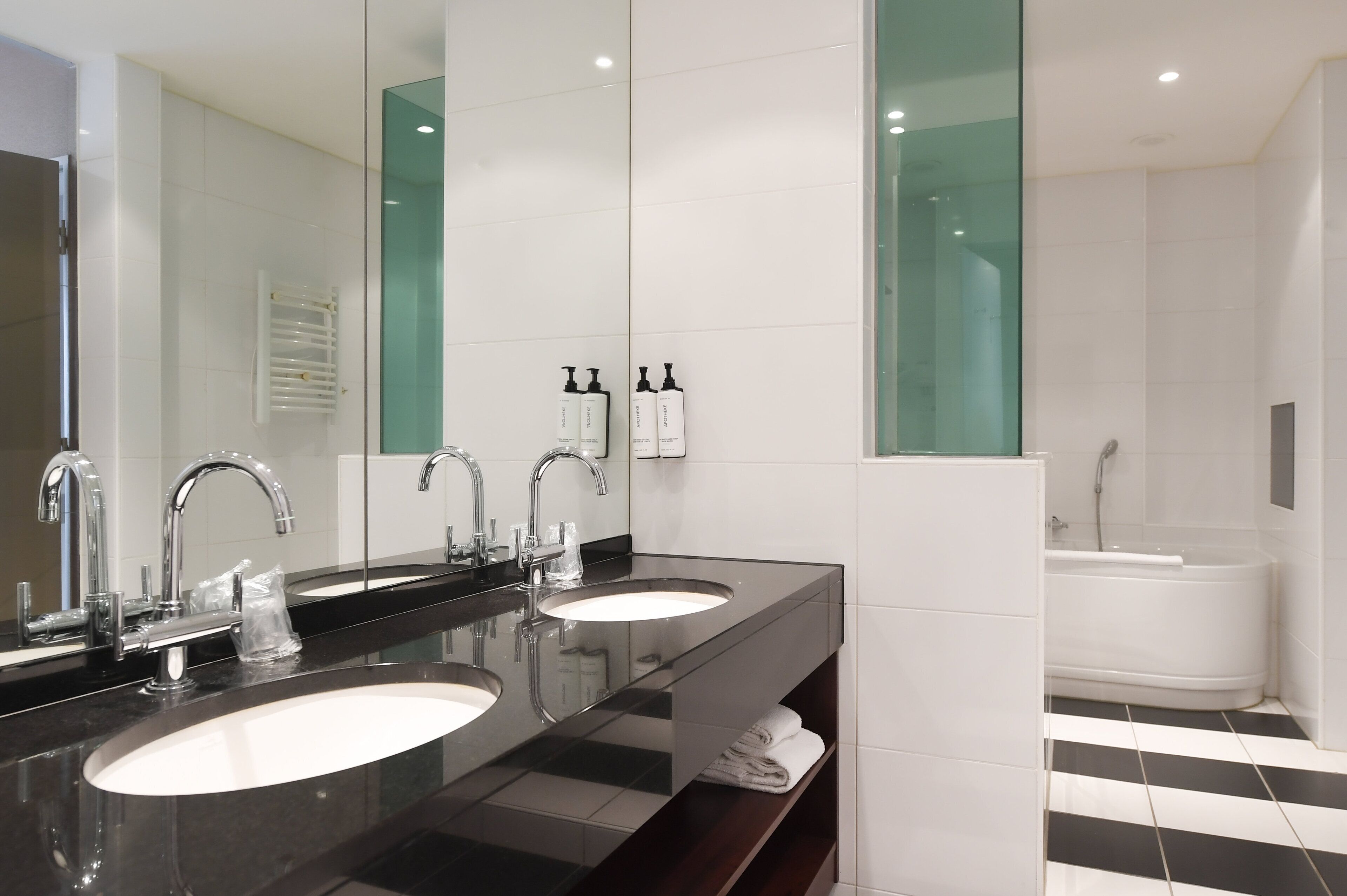 A modern bathroom with two sinks, a large mirror, and a shower area.