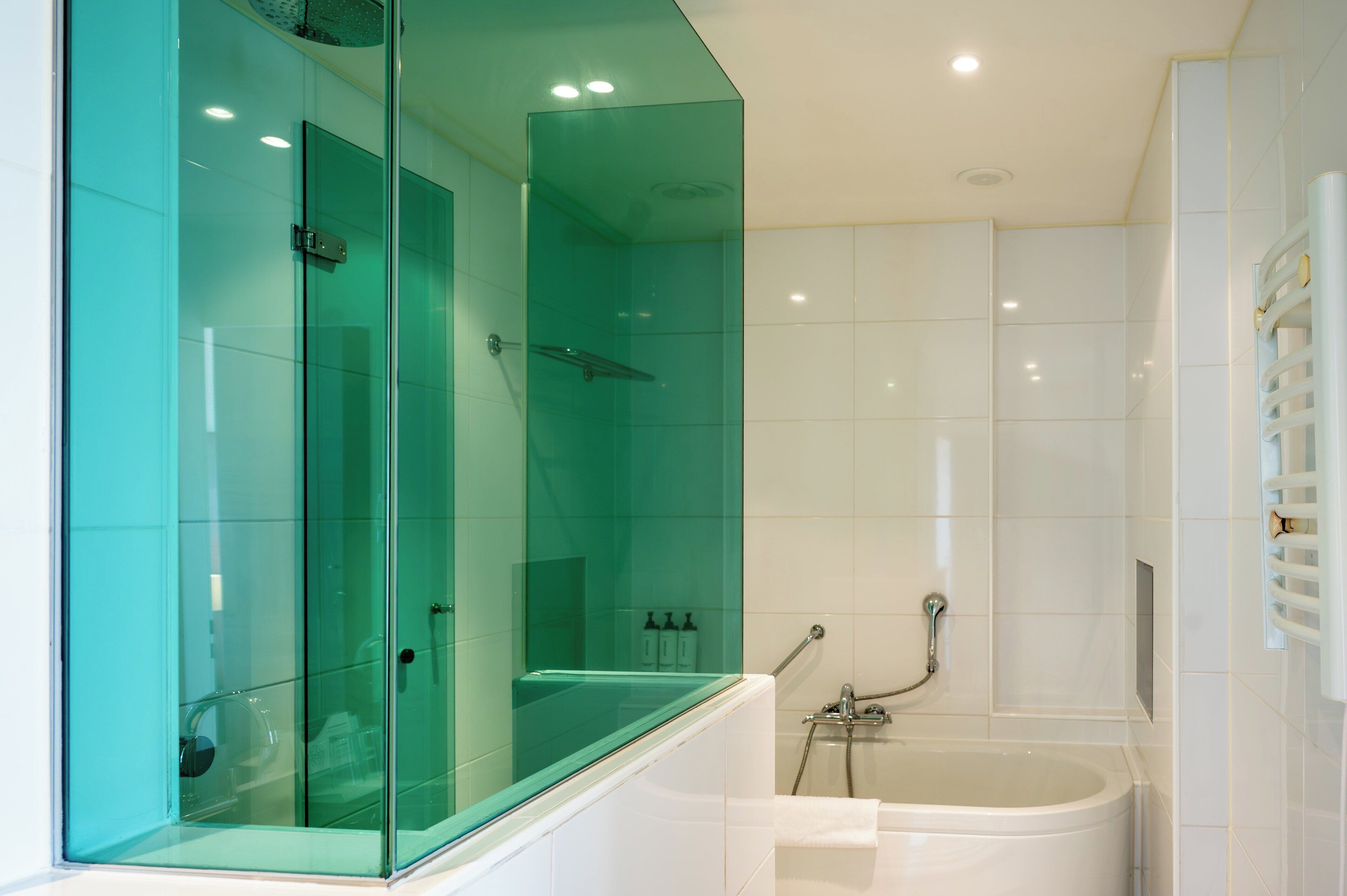A modern bathroom with a glass-enclosed shower, a bathtub, and a glass partition.