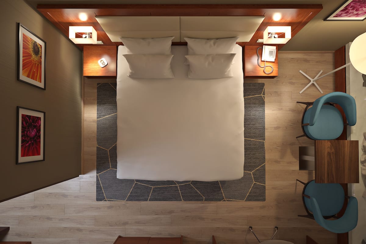 Een moderne hotelkamer met een groot bed, een houten hoofdeinde en een bureau met een stoel.
