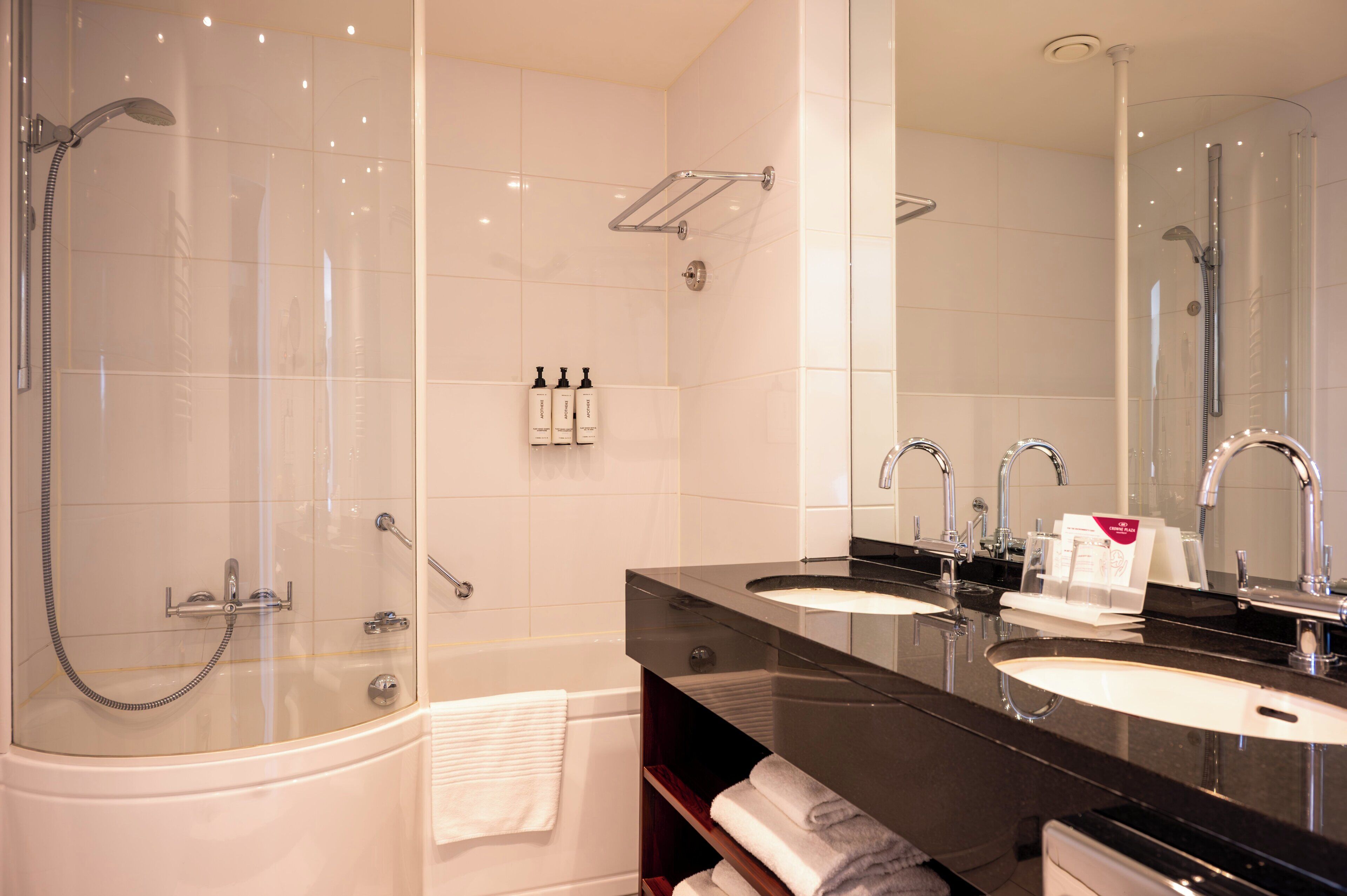 Een moderne badkamer met een douchecabine, een bad en twee wastafels.