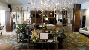 Un hall d’entrée doté d’une table en verre au centre, de plantes décoratives et d’un espace salon avec des canapés et une table basse.