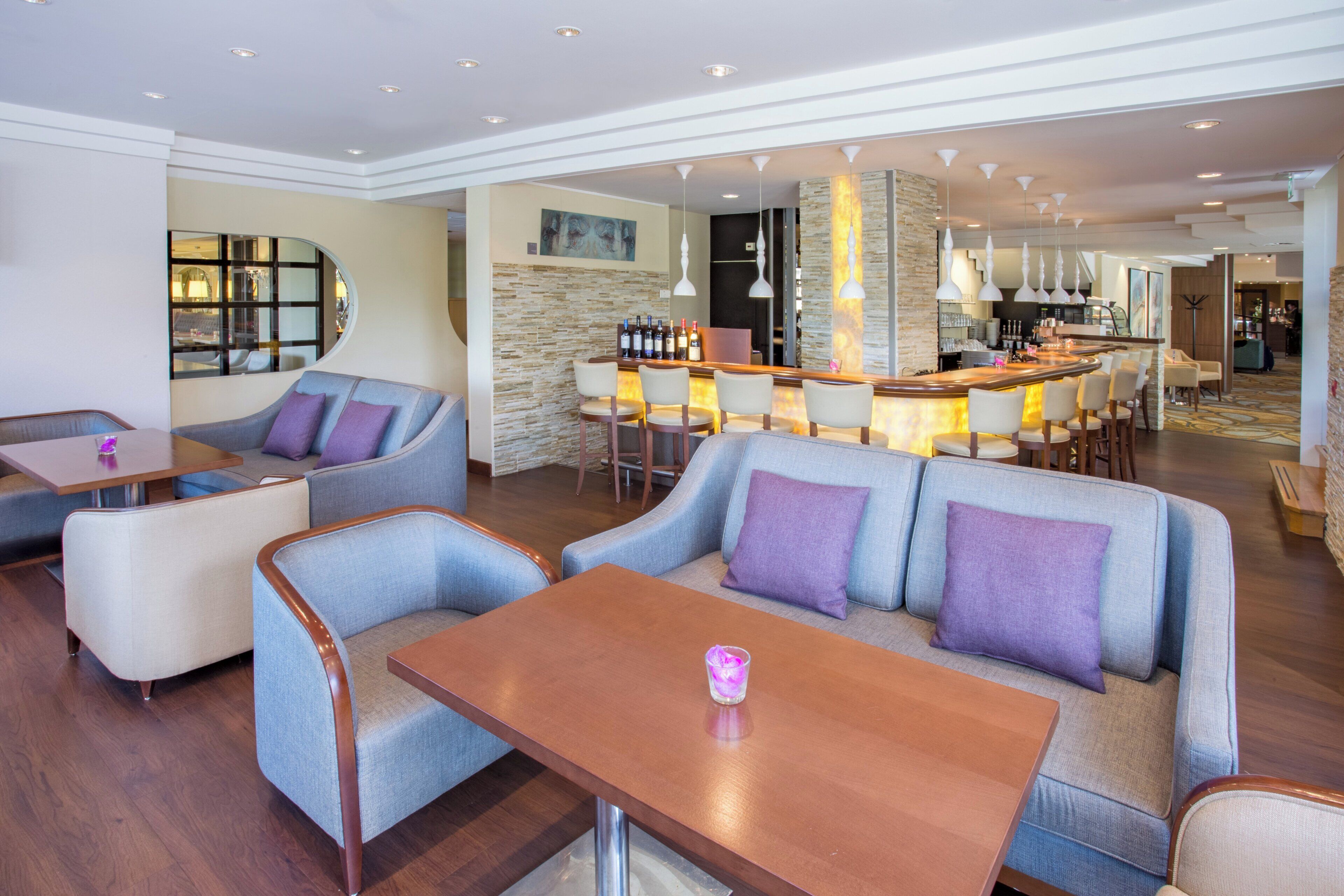 Un hall de hotel con zonas de estar, un bar y vistas a la cocina.
