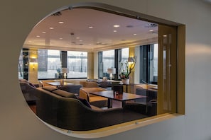 Un intérieur moderne avec un coin salon, de grandes fenêtres et une vue sur un pont.
