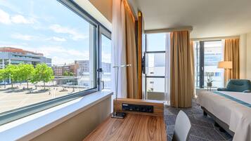 Una habitación de hotel con un ventanal grande, un escritorio, una cama y una silla.