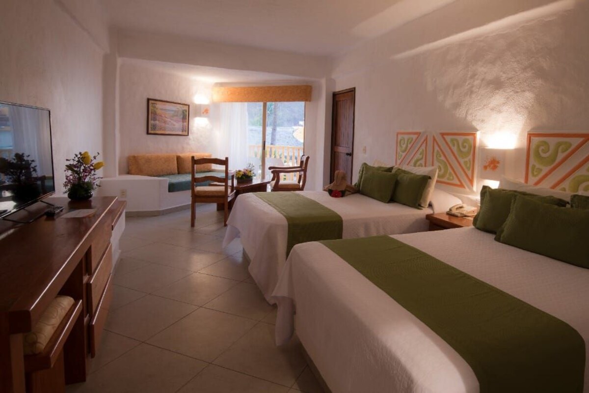 Ein Hotelzimmer mit zwei Betten, einem Schreibtisch, einem Stuhl und einem Fernseher.