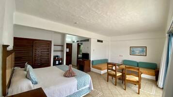 Ein Hotelzimmer mit einem Bett, einem Schreibtisch, einem Sessel, einer Couch und einem Fernseher.