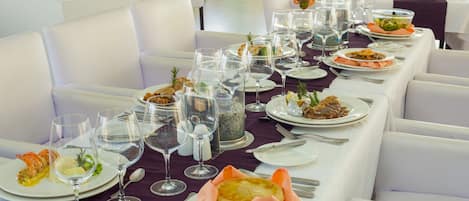 Una mesa de restaurante preparada con varios platos de comida, copas de vino y cubiertos.