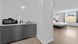 A modern kitchen with grey cabinets, a white tiled backsplash, and a microwave. - The Vista Inn (Kamloops)