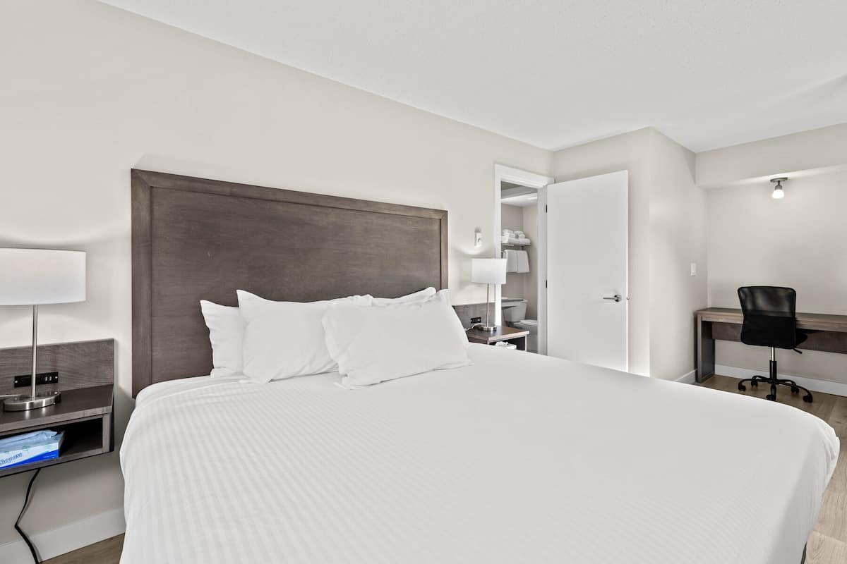 A hotel room with a large bed, bedside tables, a desk, and a chair.
