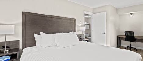 A hotel room with a large bed, bedside tables, a desk, and a chair.