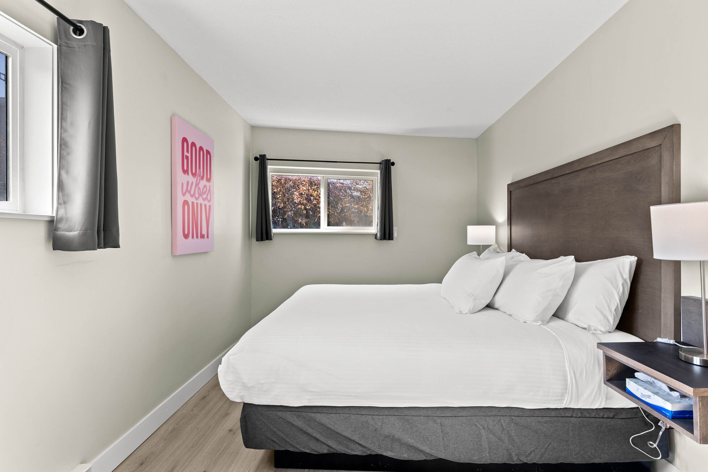 A neatly arranged bedroom with a bed, bedside table, lamp, and a window with curtains.