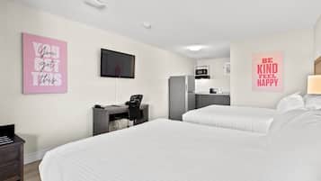 A hotel room with two beds, a desk, a chair, a TV, and kitchen appliances.