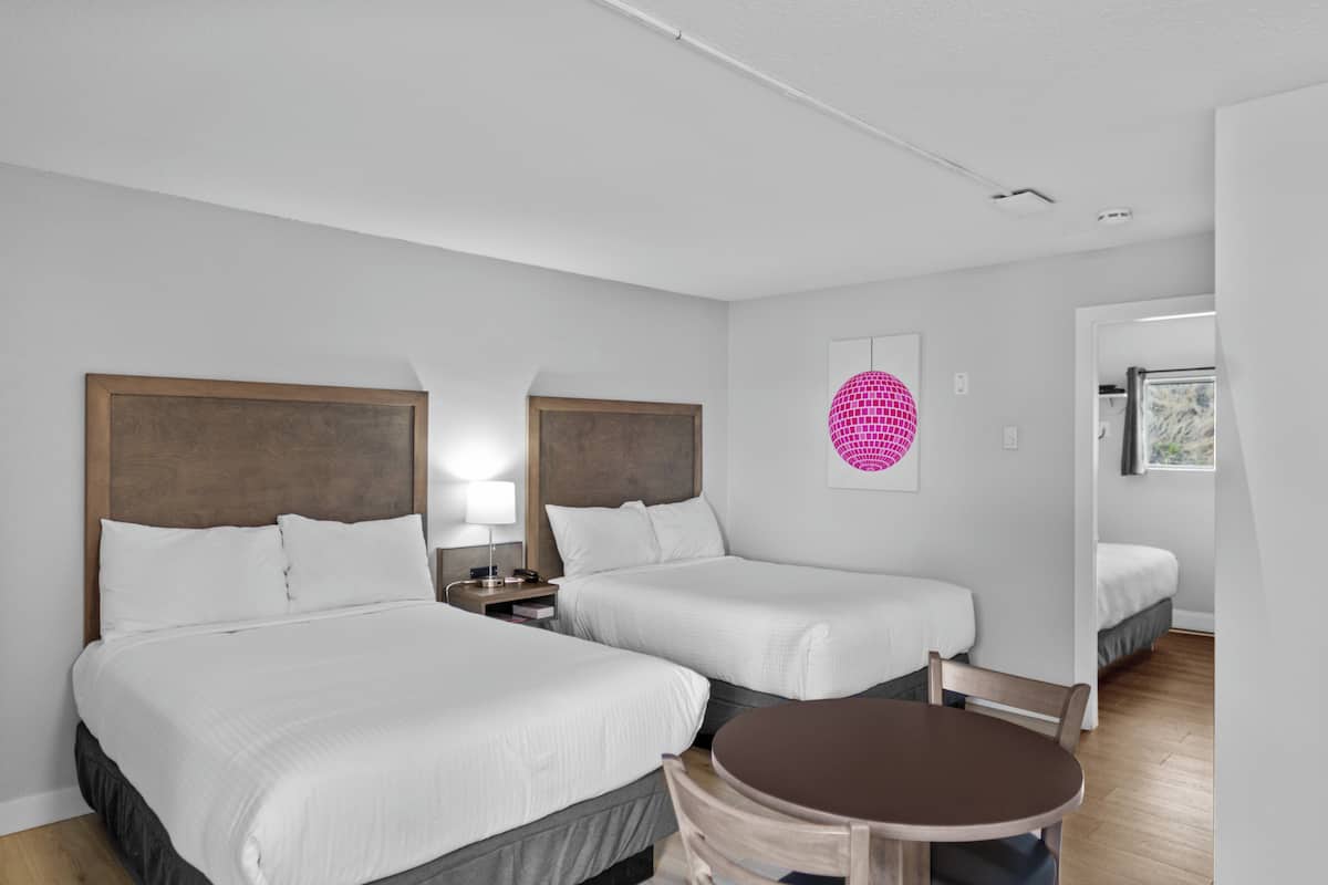 A hotel room with two beds, a round table, and a small seating area.