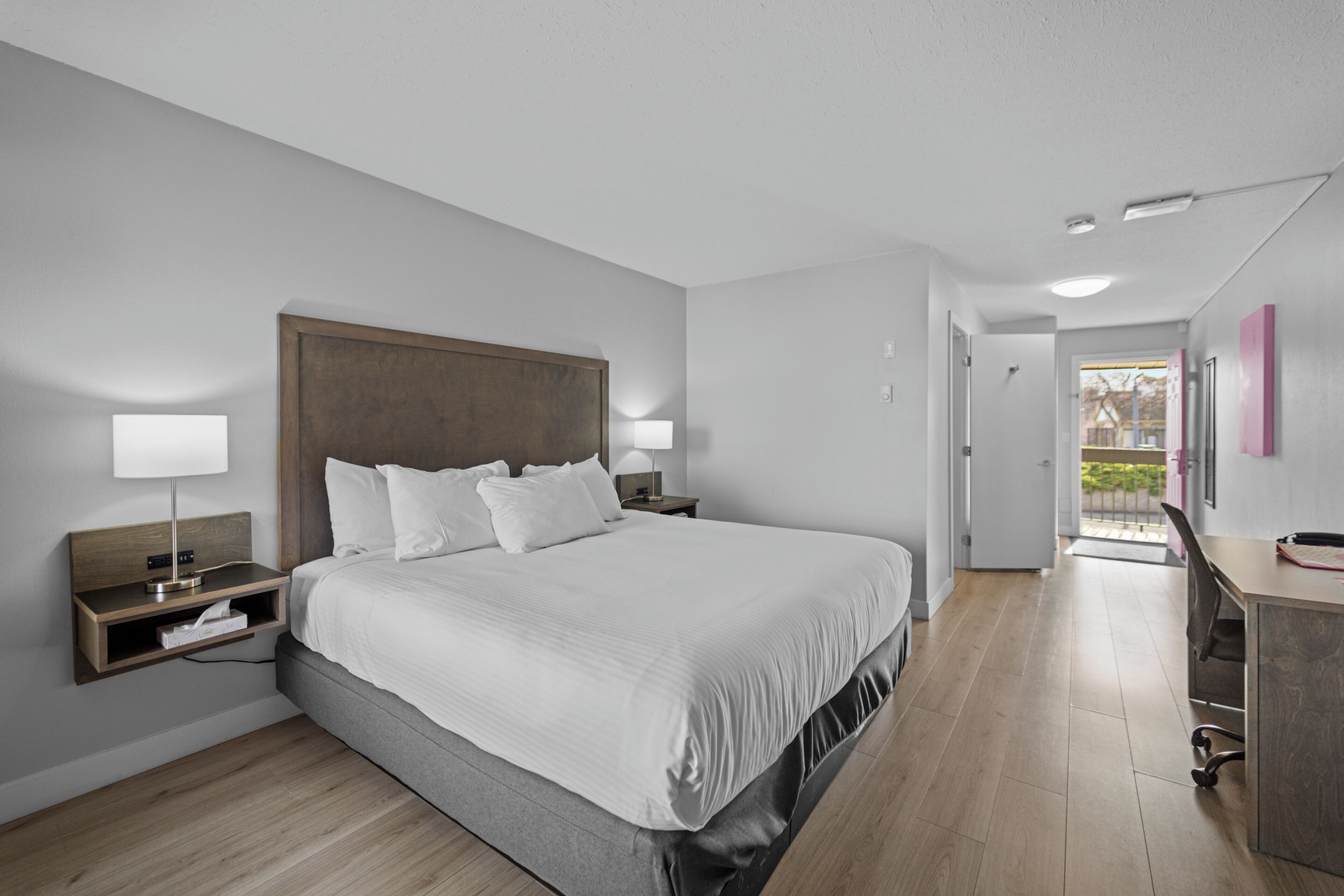 Een moderne hotelkamer met een groot bed, nachtkastjes, een bureau en uitzicht.