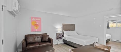 A modern hotel room with a bed, a sofa, a table, and a small desk.