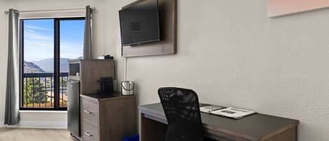 Una habitación moderna con escritorio, silla y televisor montado en la pared.