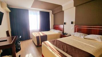 A hotel room with two beds, a desk, and a chair.
