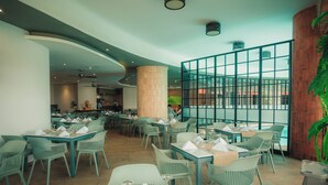 En restaurant med borde, stole, en stor søjle og udsigt gennem en glasvæg.