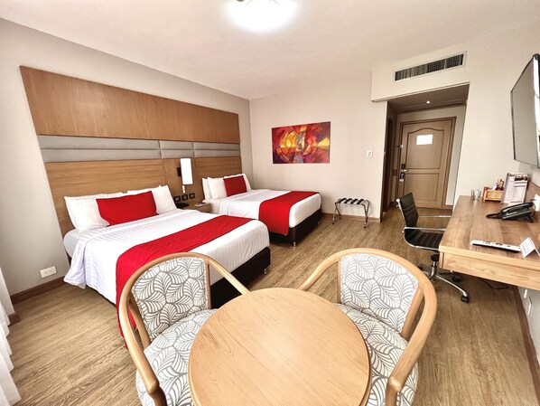 A hotel room with two beds, a desk, a chair, and a painting on the wall. - Hotel Dann Carlton Cali (Cali)